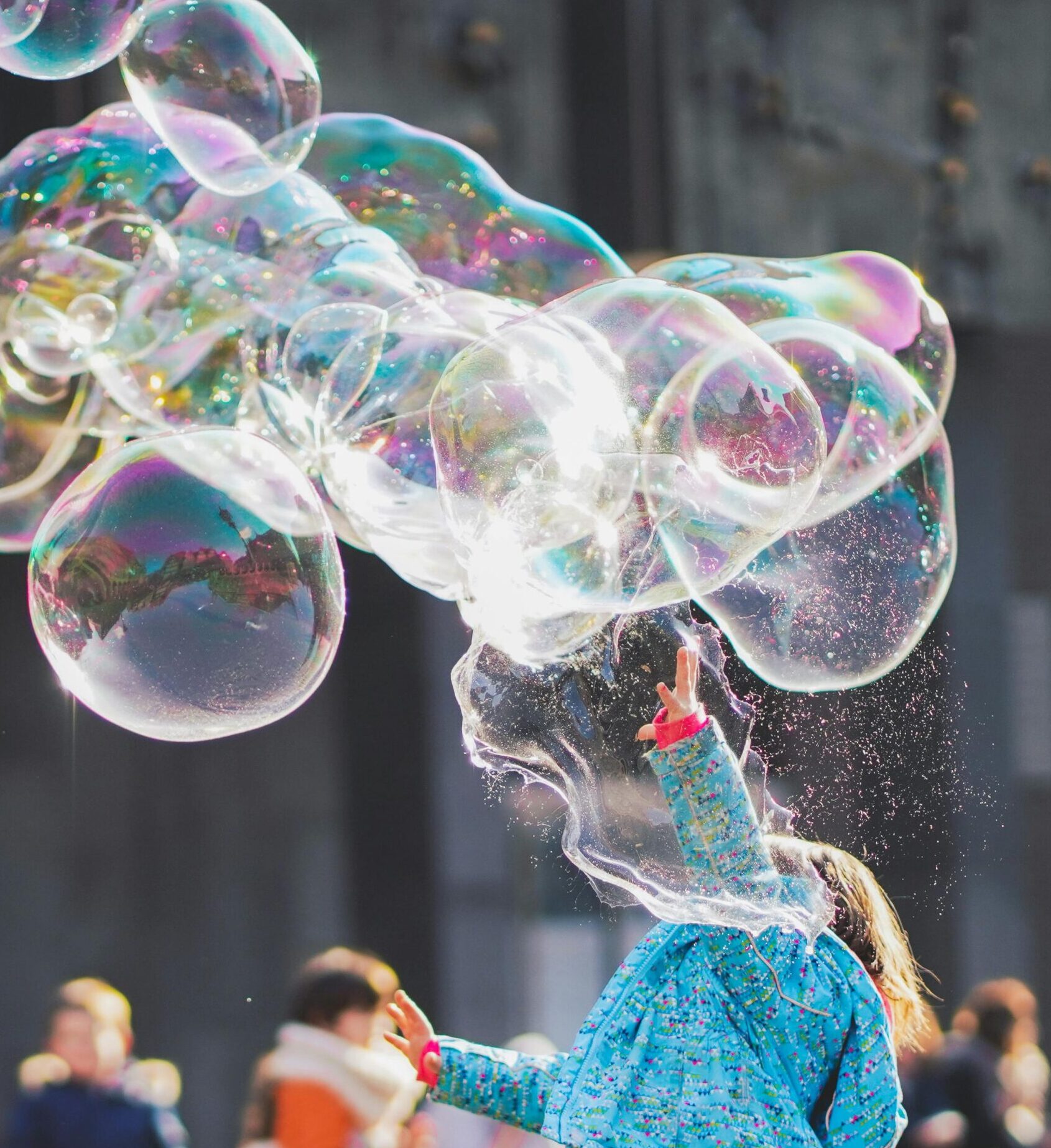 A child delights in chasing and popping giant bubbles in an outdoor setting.